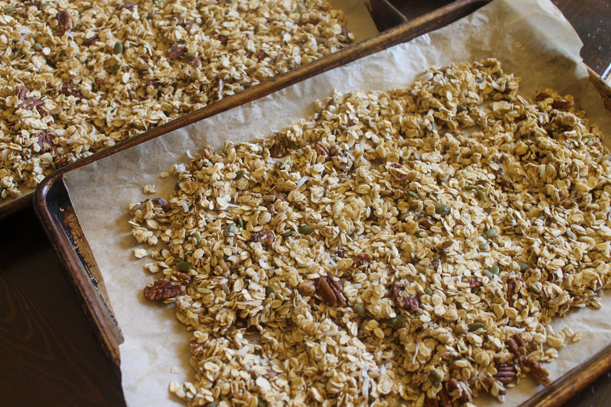 Two sheet pans of granola ready to bake.