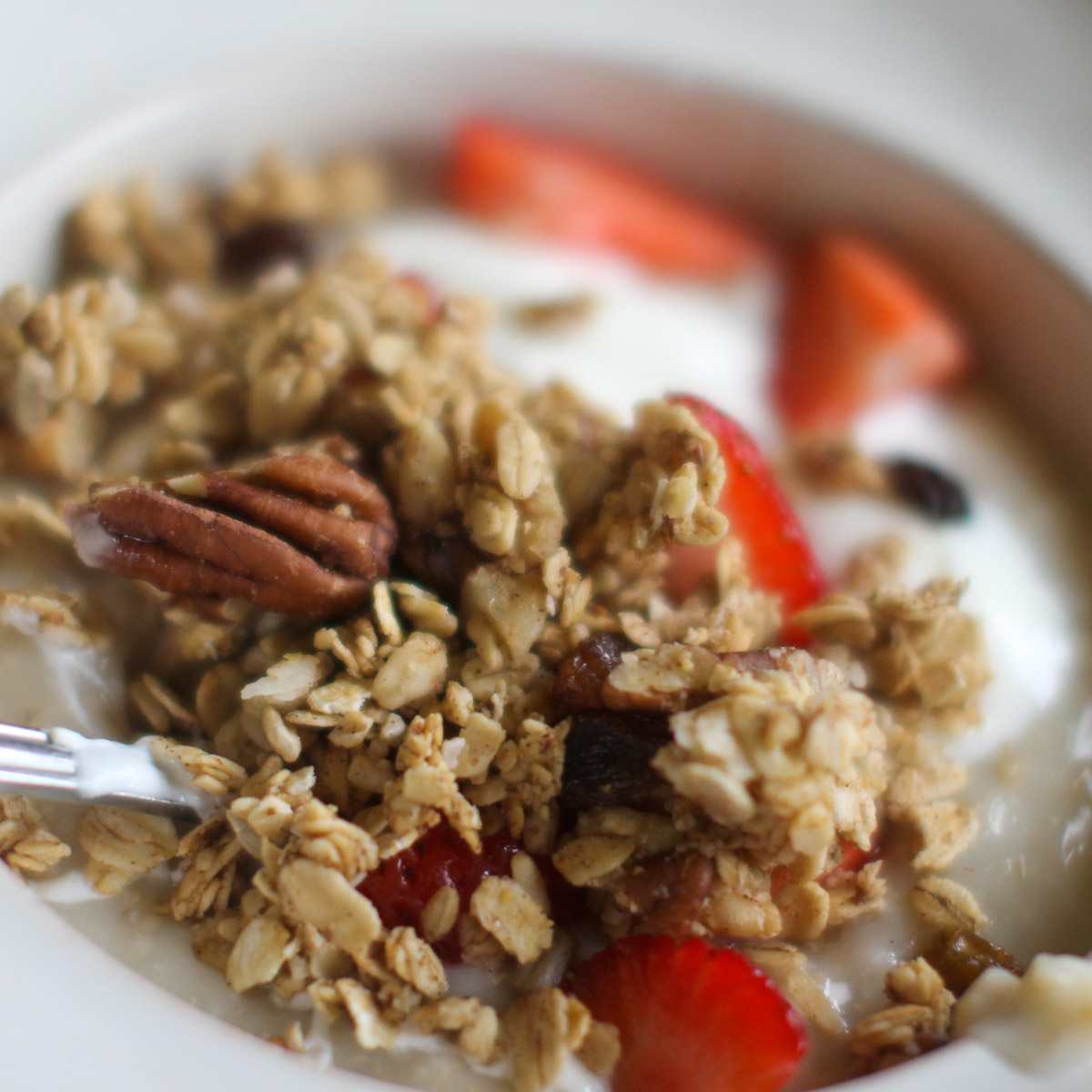 A bowl of oatmeal topped with applesauce granola and strawberries.