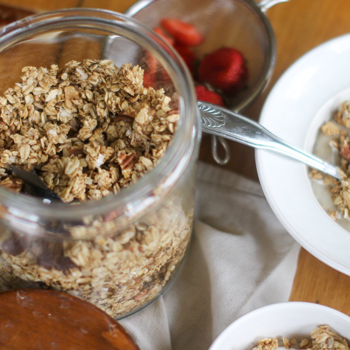 The opened jar of Applesauce granola and a strainer with berries.