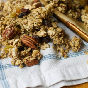Homemade granola on a sheet pan and white kitchen towel.
