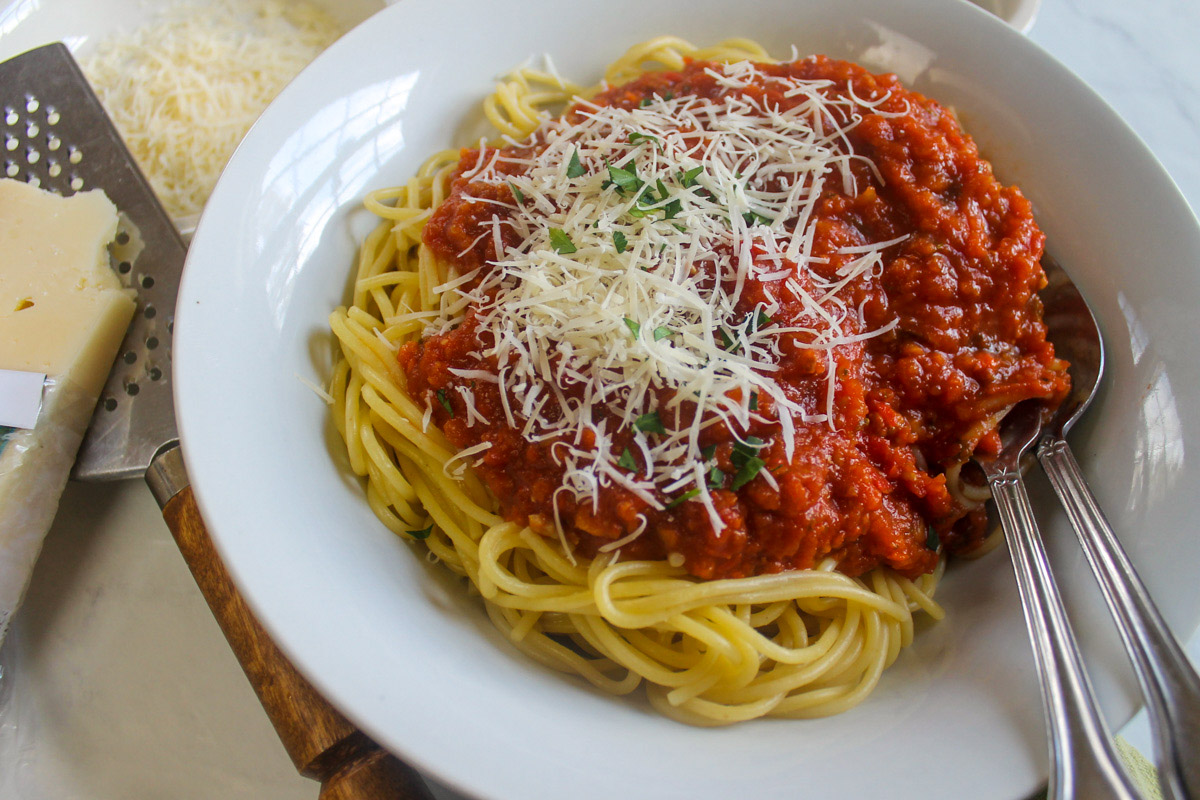 A bowl of bolognese sauce with sausage over pasta.