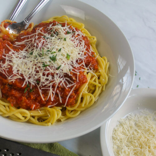 A bowl of Italian sausage bolognese sauce served over spaghetti.