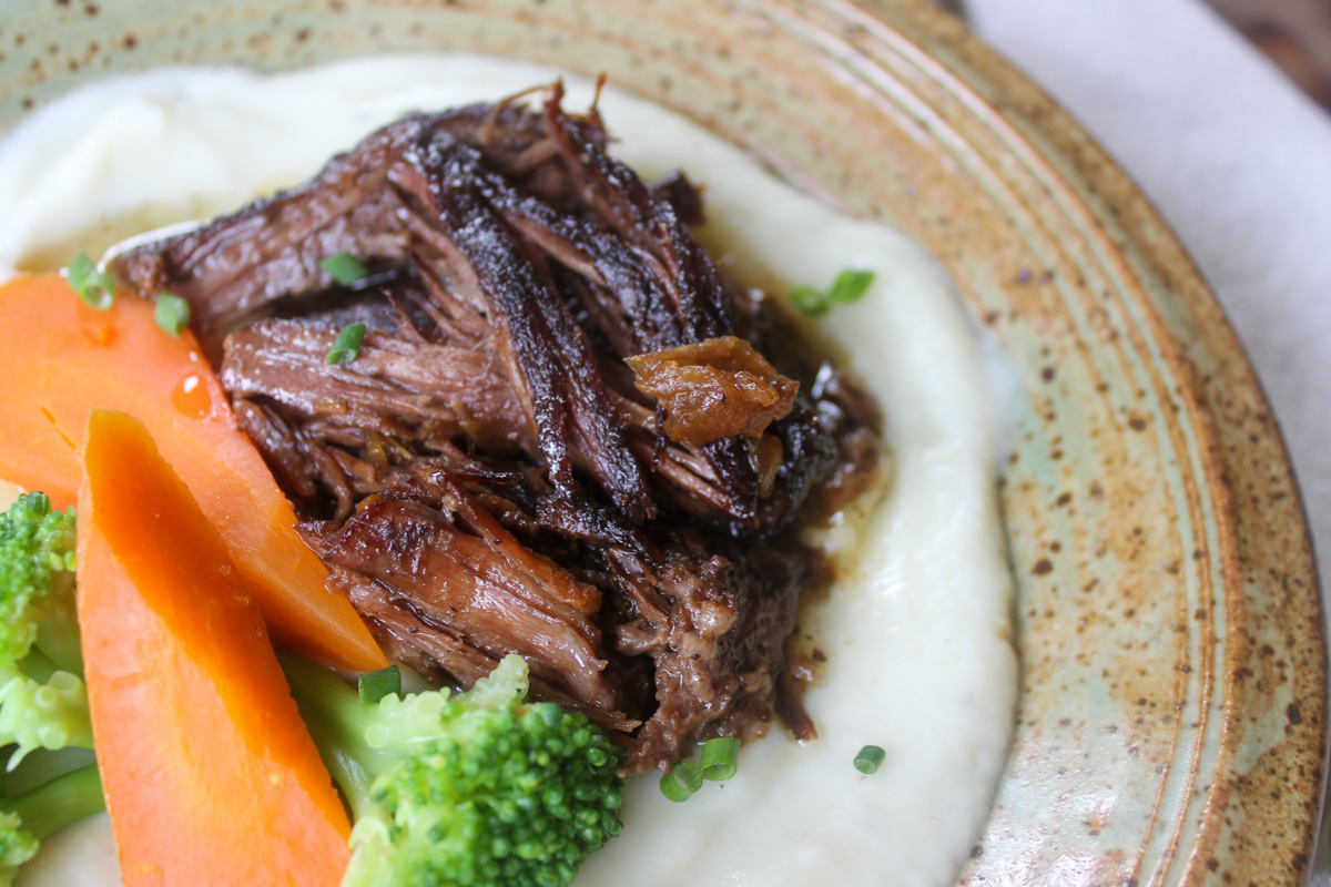 Tender beef pot roast with vegetable sides.
