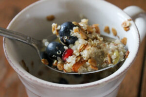 A spoonful of breakfast quinoa porridge with berries and granola topping.