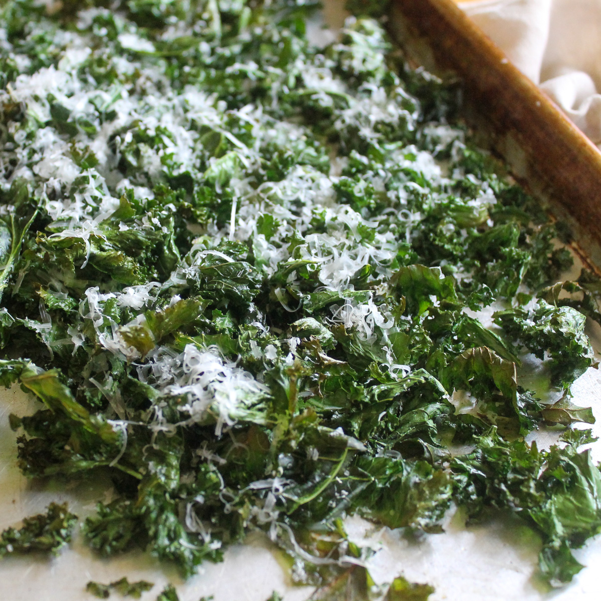 A pan of oven roasted kale chips with Parmesan cheese.