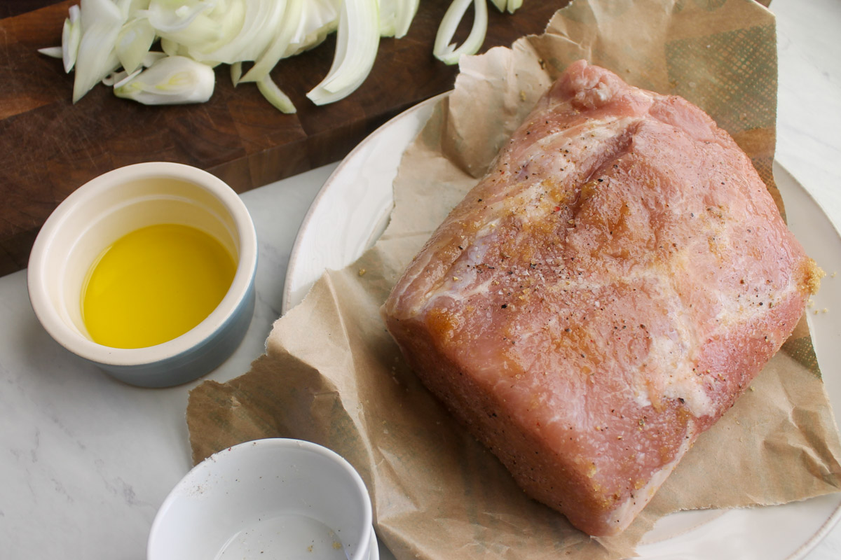 Seasoning the raw pork loin roast with salt, pepper and brown sugar.