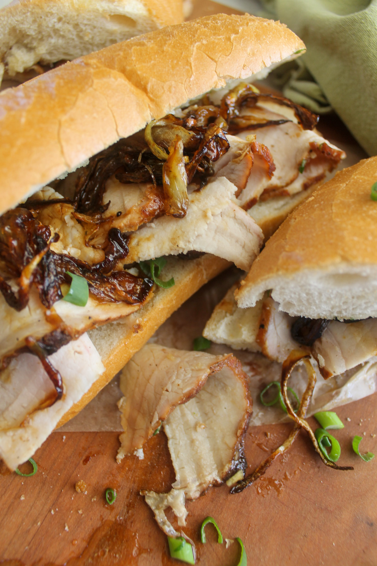 Hoagie buns piled with shaved pork roast and onions sandwiches.