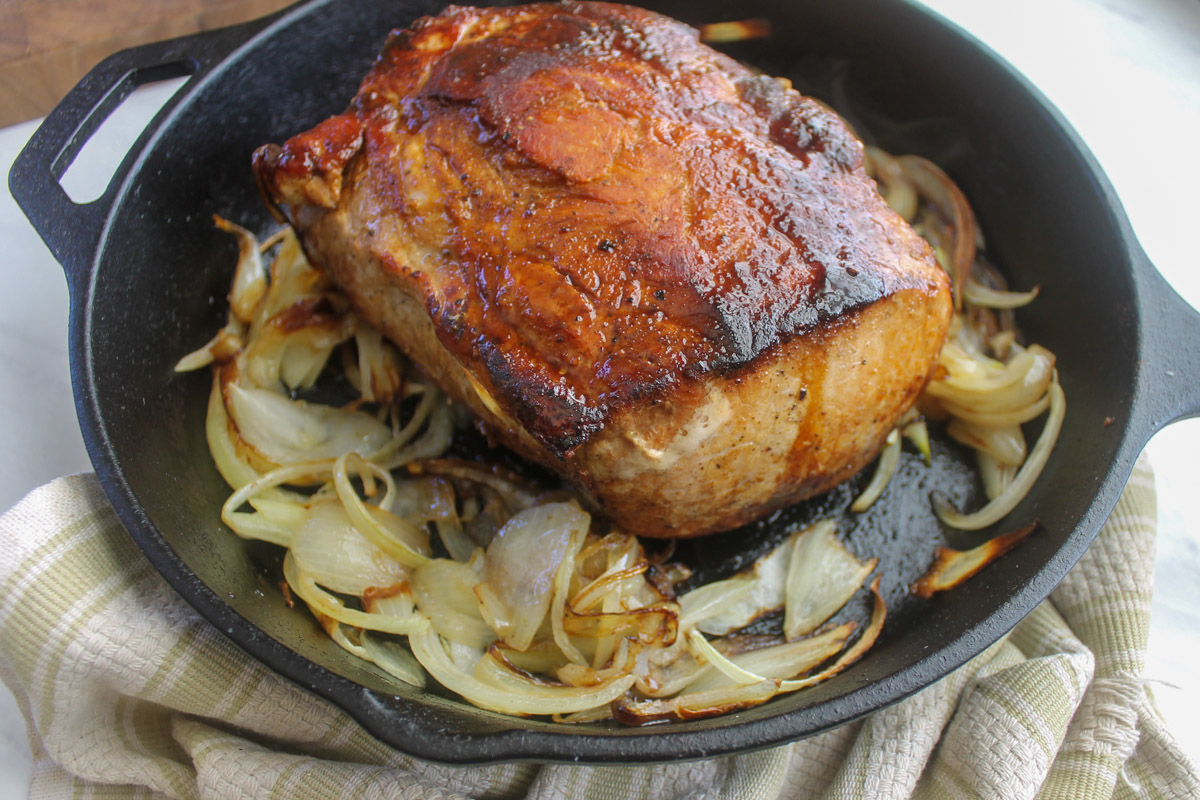 The pork roast halfway through cooking in the oven with the onions beginning to caramelize.