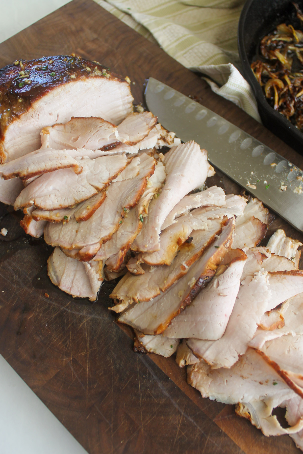 Thinly shaved pork roast on a cutting board for sandwiches.