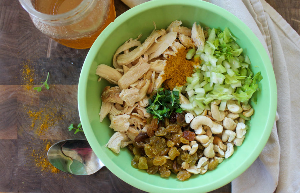 Bowl of curry chicken salad ingredients ready to be mixed.