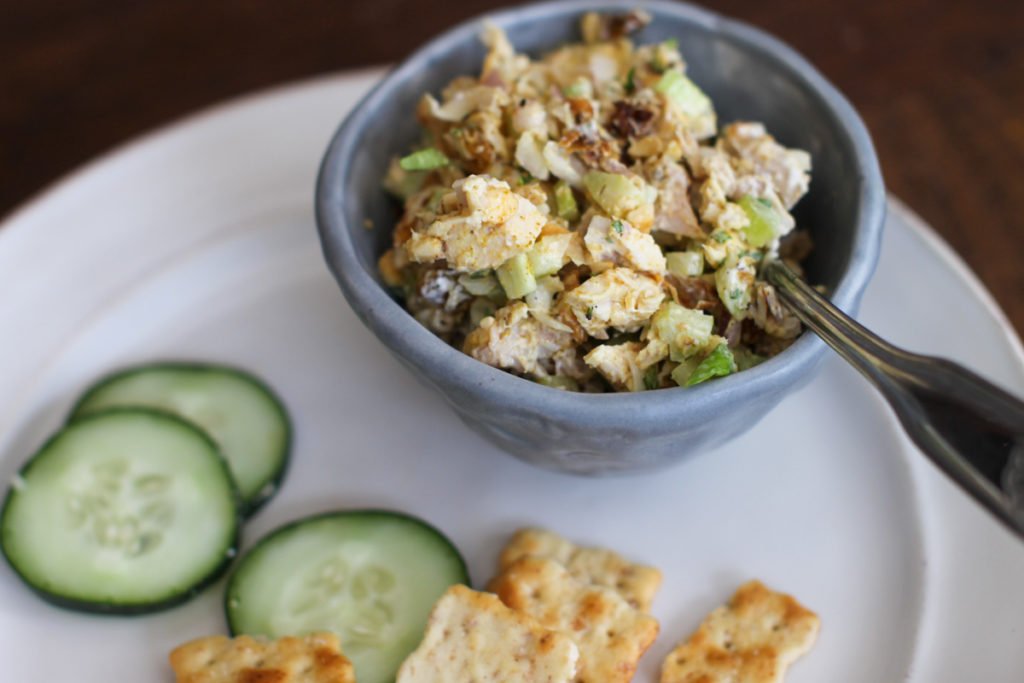 Curry Chicken Salad served in a bowl as a dip with crackers and cucumber.