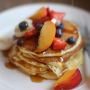 Mom's Buttermilk Pancakes piled with strawberry, banana, peaches and blueberry.