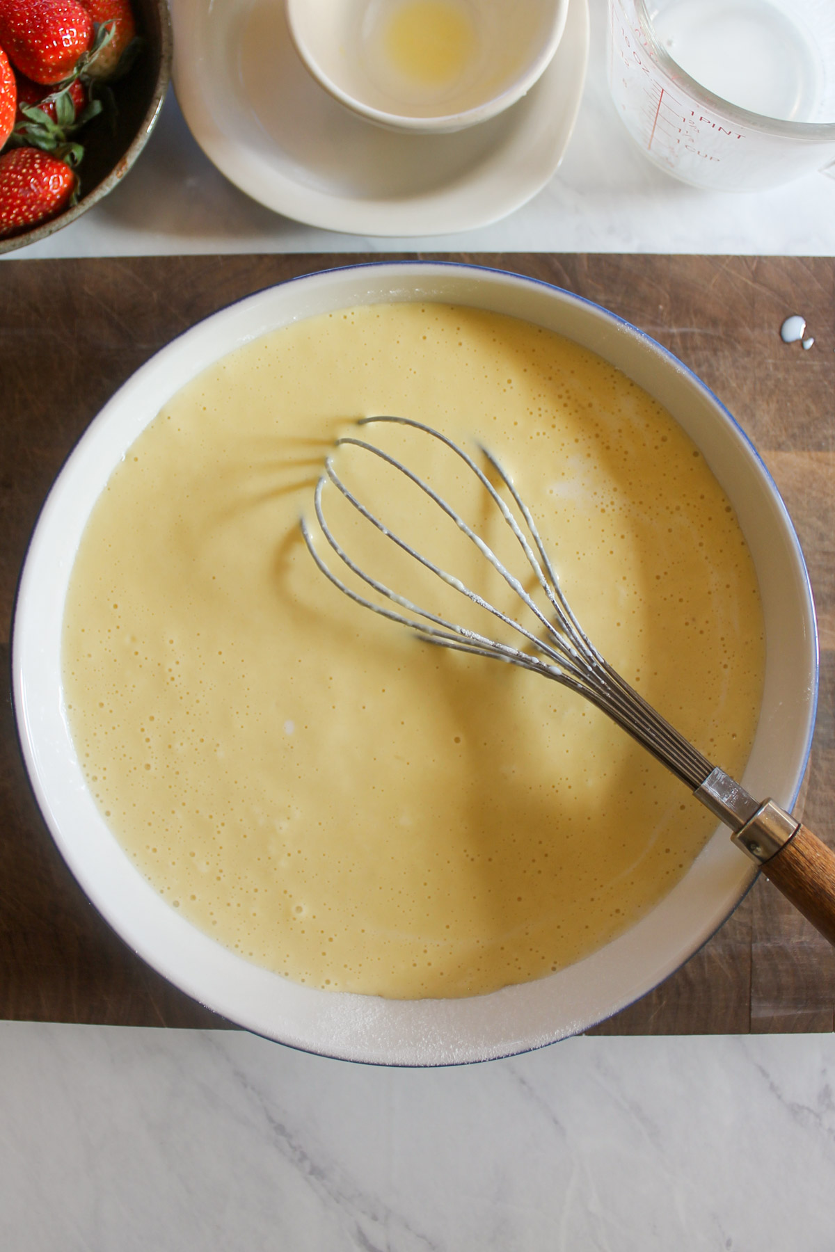 A bowl of pancake batter with a whisk.