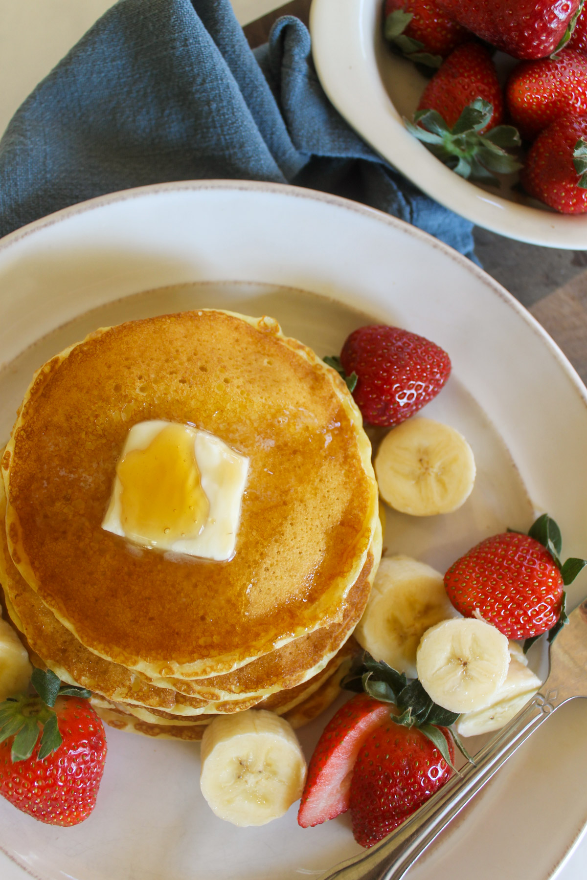 Buttermilk pancakes on a plate surrounded by fruit.