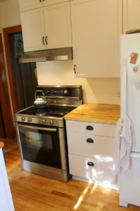 Oven with new butcher block counters and painted white cabinets.