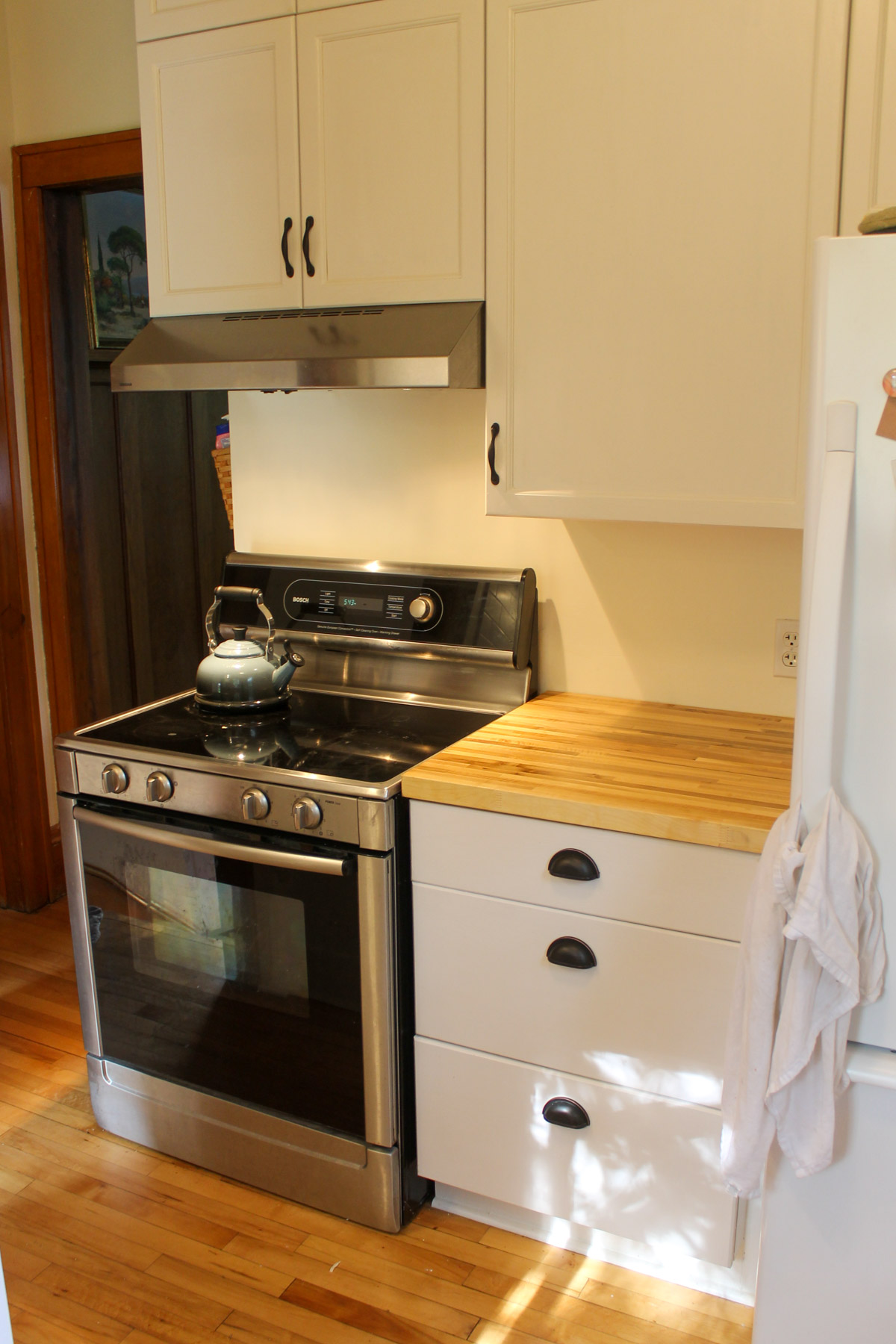 The updated kitchen with painted white cabinets, new black hardware and butcherblock counters.