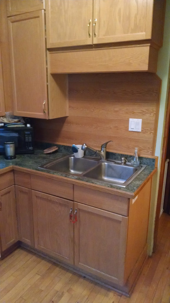 Sink area before the kitchen upgrade with old oak cabinets and ugly backsplash.