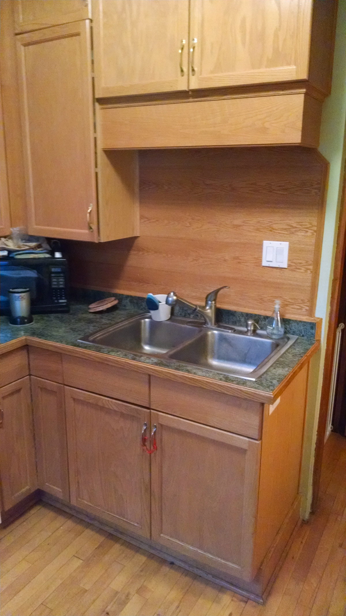 A before photo of the kitchen with the old floor to ceiling tan oak cabinets.
