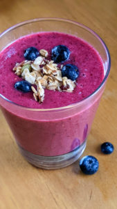 Bright pink berry smoothie with blueberry and granola topping.