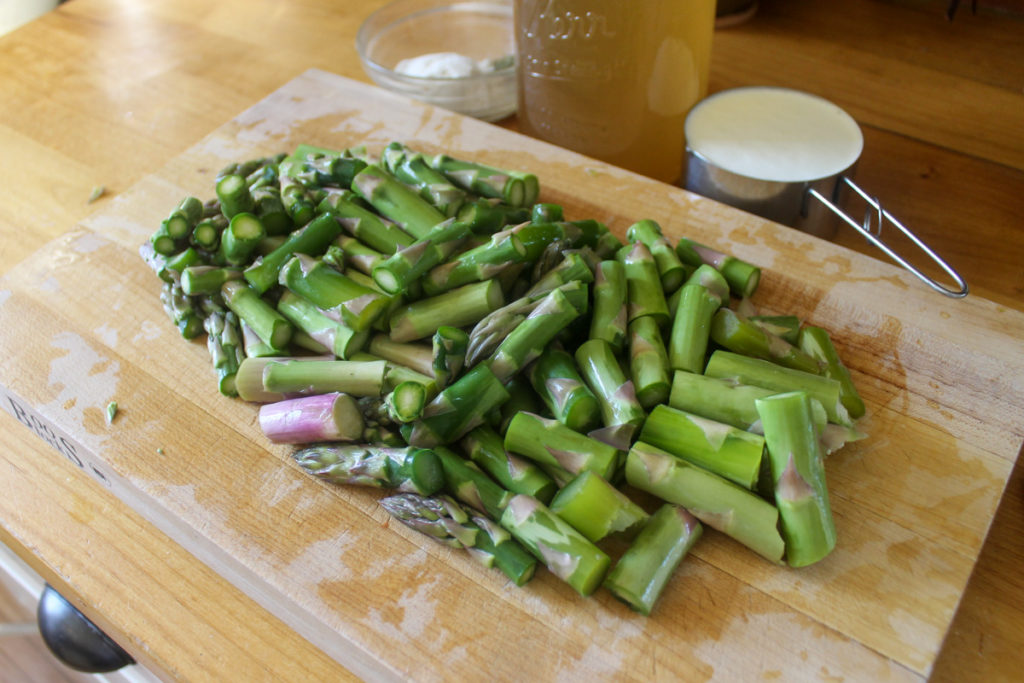 Chopped asparagus on a cutting board for soup.