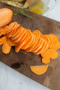 Thinly peeled and sliced sweet potatoes on a cutting board.