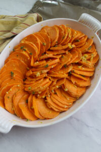 The sweet potato slices coated in the honey garlic butter and arranged in a casserole dish.