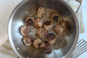 Meatballs being searing in a pan