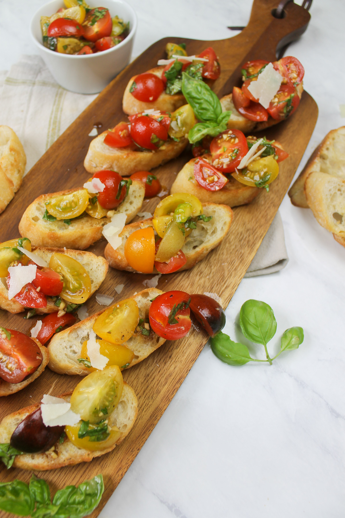 A wooden cutting board with cherry tomato bruschetta on crostini.