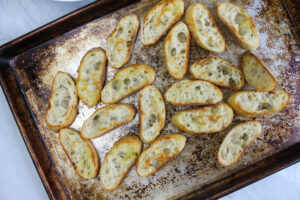 Baguette slices baked in the oven to make crostini for bruschetta.