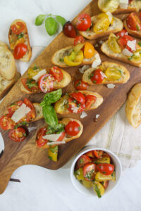 Bruschetta with cherry tomatoes served on a wooden plank board.