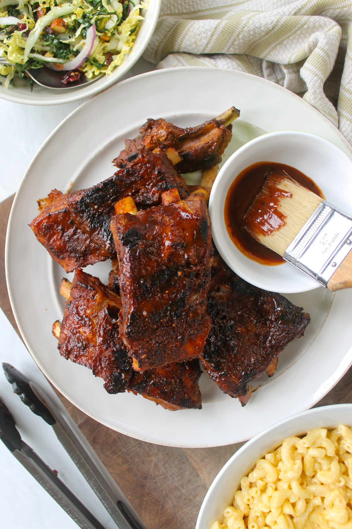 Honey mustard dry rub ribs on a plate with a bowl of bbq sauce with a brush.