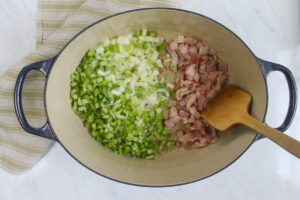 Raw bacon and onion and celery beginning to cook in the soup pot.