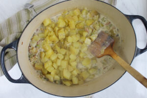 Adding the boiled potatoes to the pot of potato corn chowder soup.