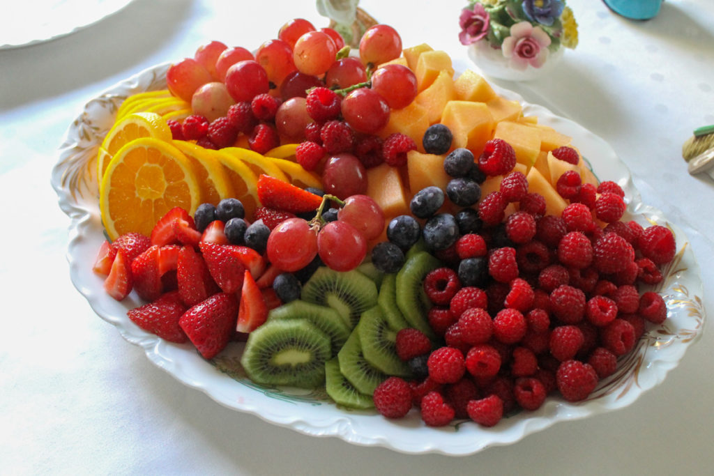 A fresh fruit tray with melon, kiwi, grapes, oranges and berries.