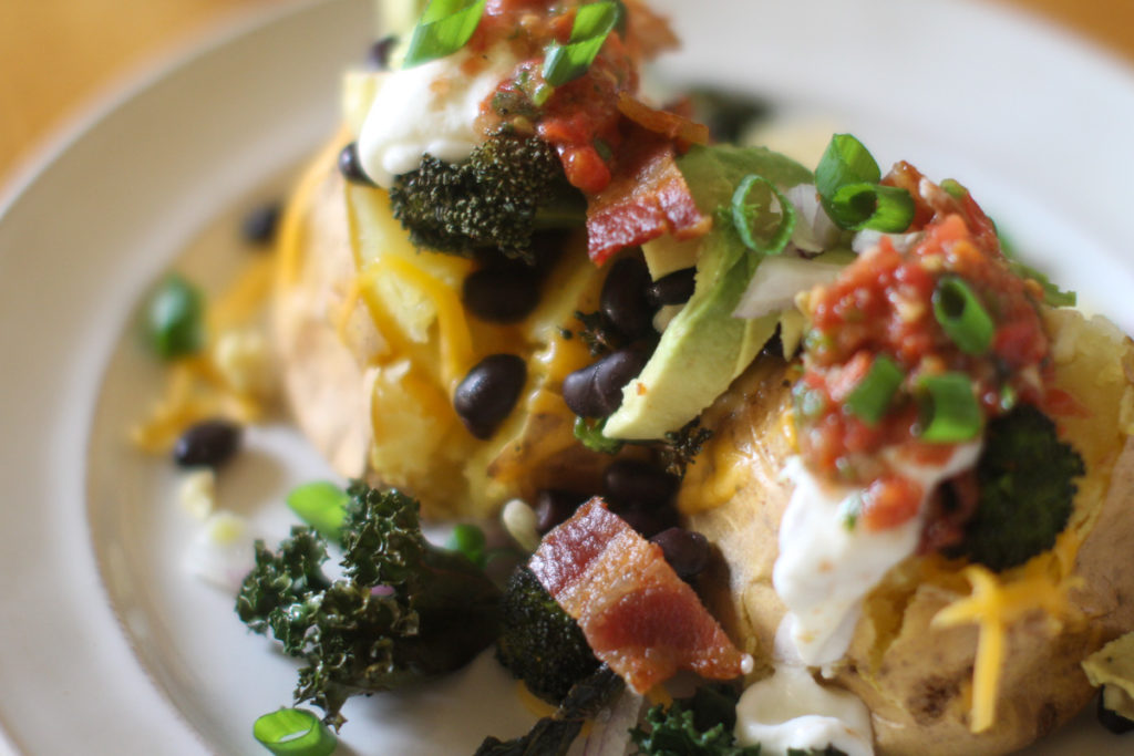 Close up of loaded baked potatoes with toppings.