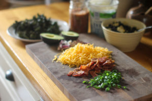 A cutting board of loaded baked potato bar toppings.