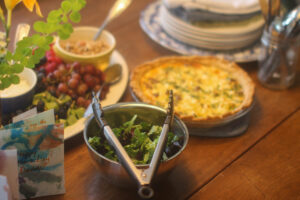 A brunch table with quiche, salad, and fruit.
