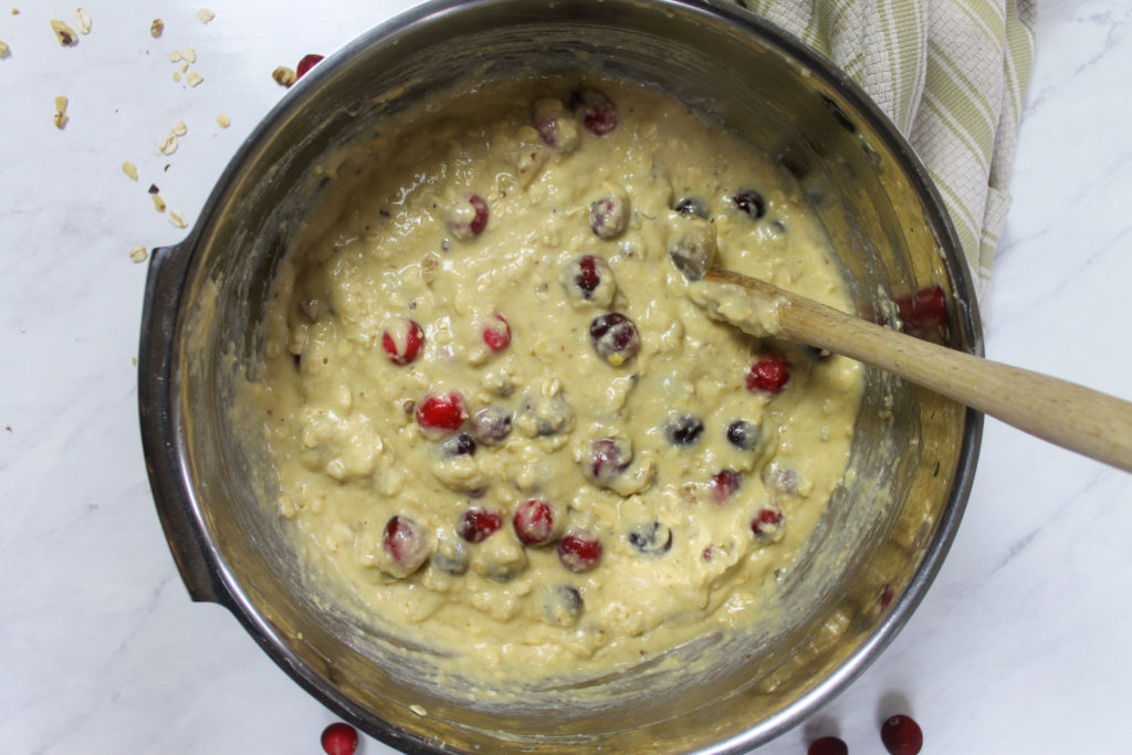 A bowl of mixed batter for Cranberry Muffins with a spatula.