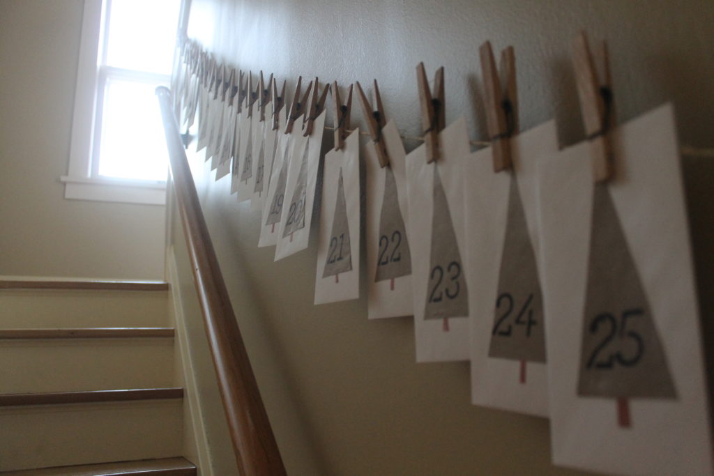 An Advent Calendar hanging in a stairwell with envelopes cloths-pinned to a string.