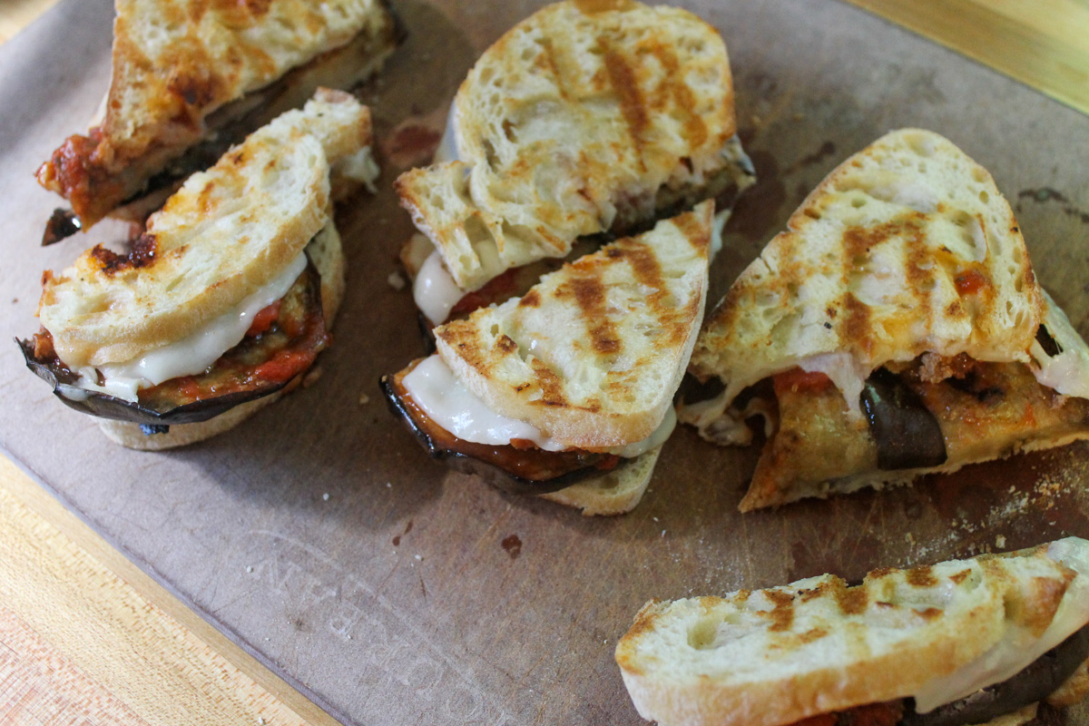 Sliced eggplant paninis on a cutting board.