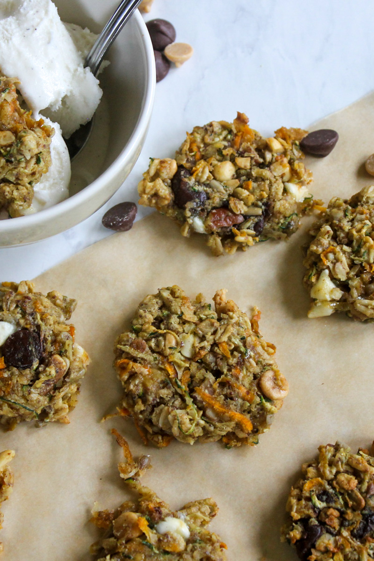 Protein zucchini banana cookies on parchment paper with extra chocolate chips.