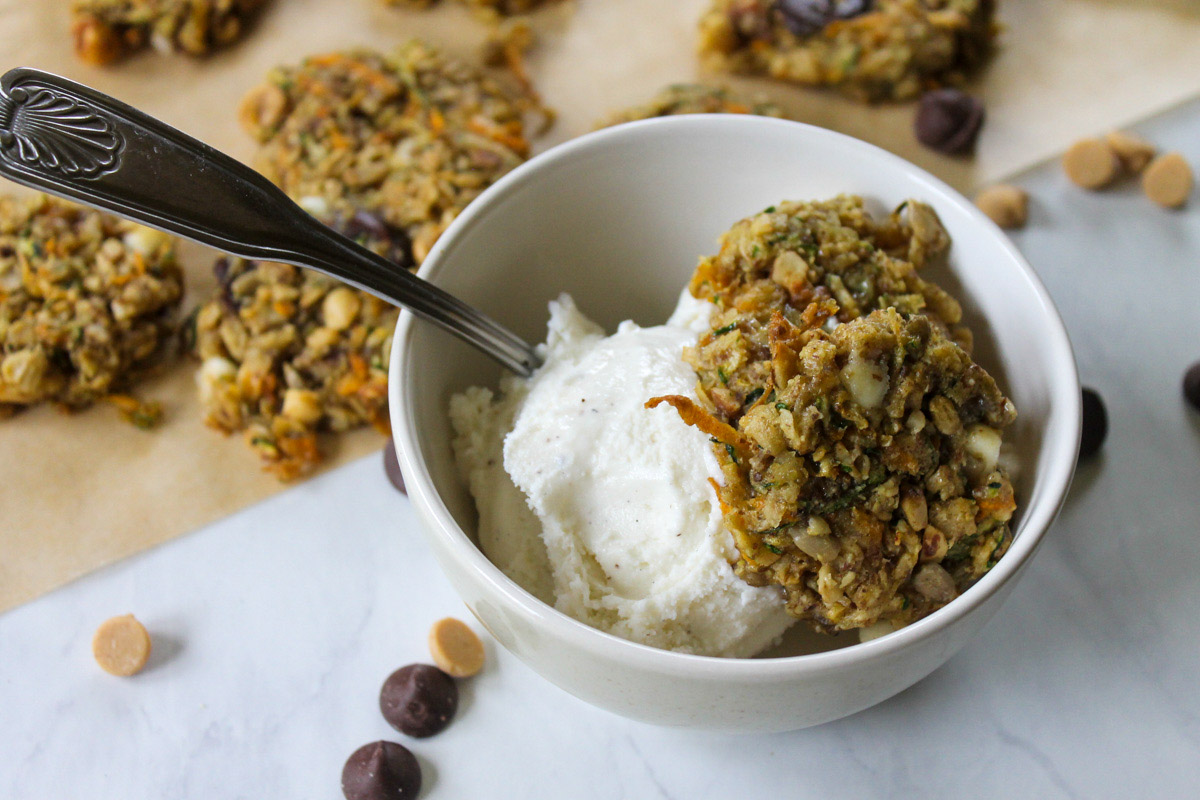 A bowl of ice cream with zucchini carrot cookies and more cookies on parchment paper.