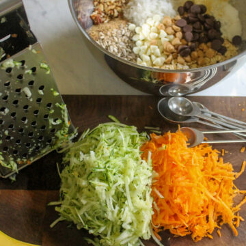 Healthy zucchini banana cookies ingredients on a cutting board, shredded zucchini and carrots.