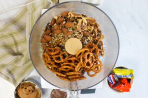 A food processor ready to pulse pretzels, nuts and seeds.