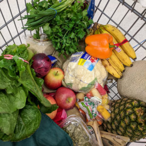 A grocery cart full of produce, not in produce bags.