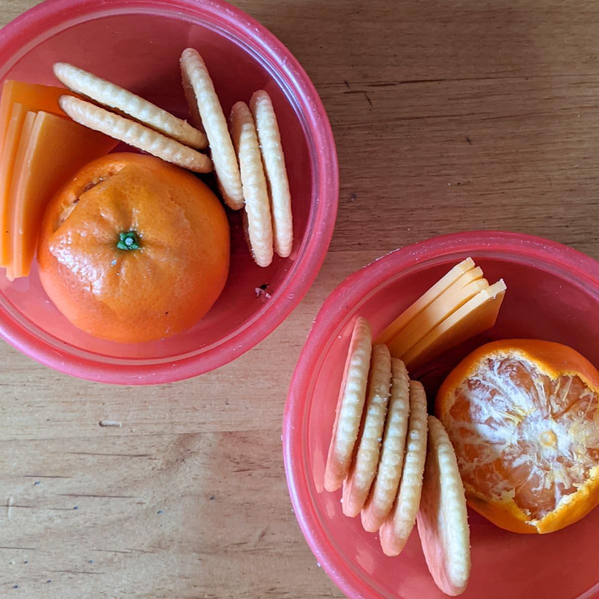 Two kids snacks with little cutie oranges, crackers and slices of cheese.