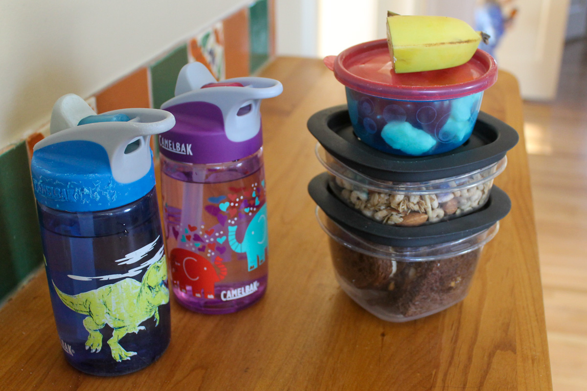 A stack of snack packs ready to go with kids water bottles.