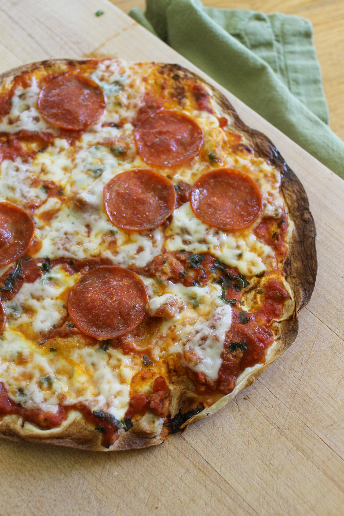 A kid's lunch pizza made on a large tortilla with cheese and pepperoni.