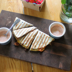 A kid's lunch quesadilla made in a panini press with cups of salsa ranch sauce.