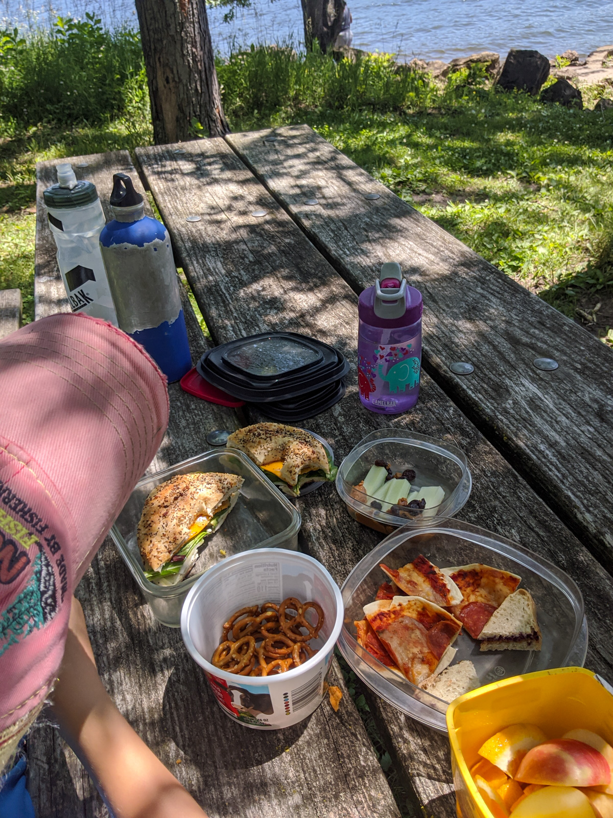 A kid's lunch to go on a picnic table by a lake.